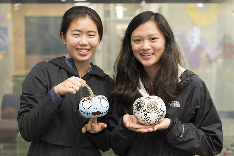 Two students holding painted pumpkins.