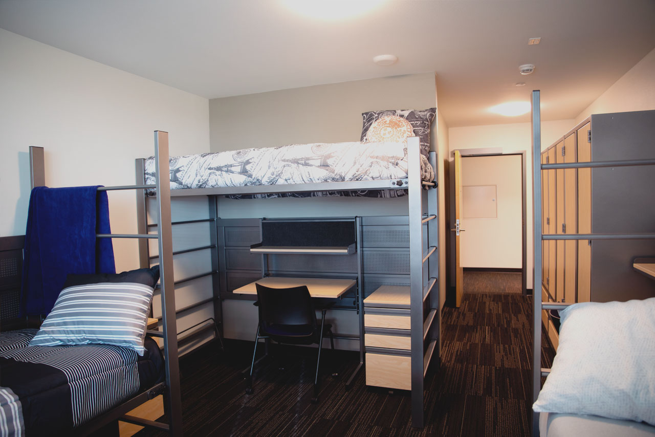 A 3-person room in McCarty Hall three twin beds and a desk and chair.