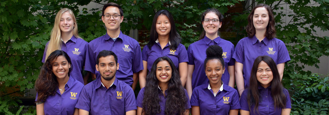A group of students smiling wearing matching purple shirts.