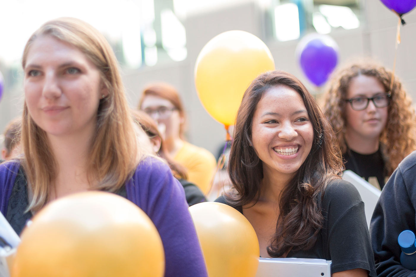 Students smiling with purple and gold balloons.