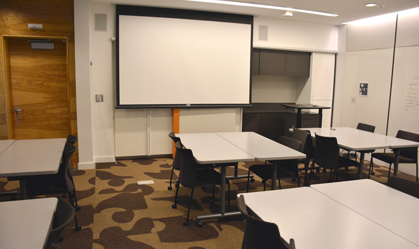 A room with tables, chairs, and projector.