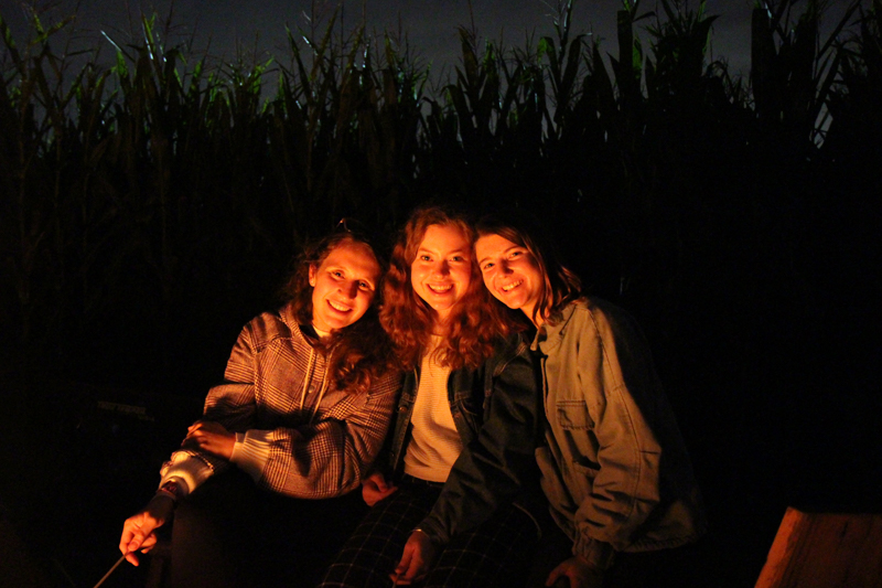 Three students sitting around a fire.