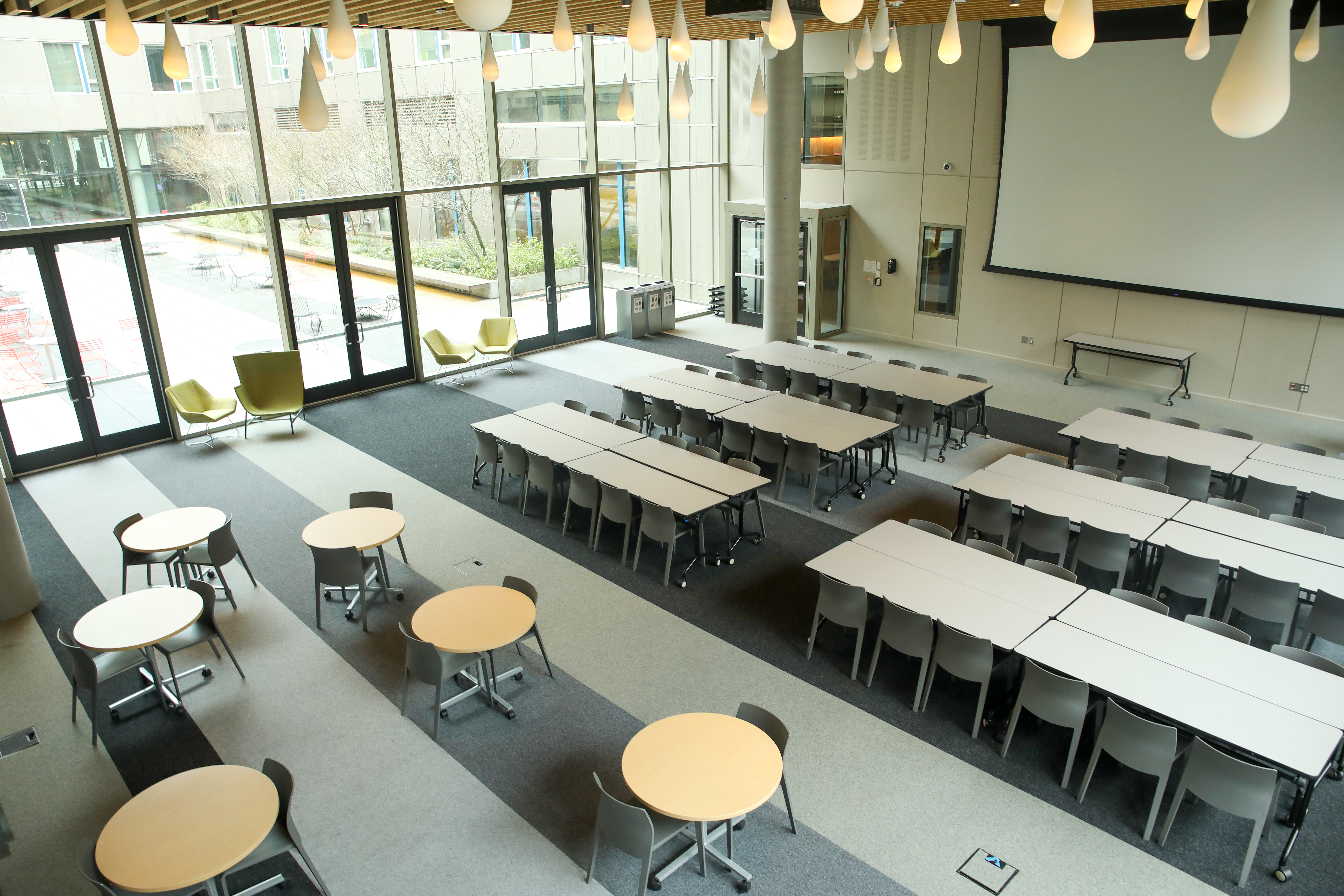 The Maple Hall Great Room with a projector screen and many tables and chairs.