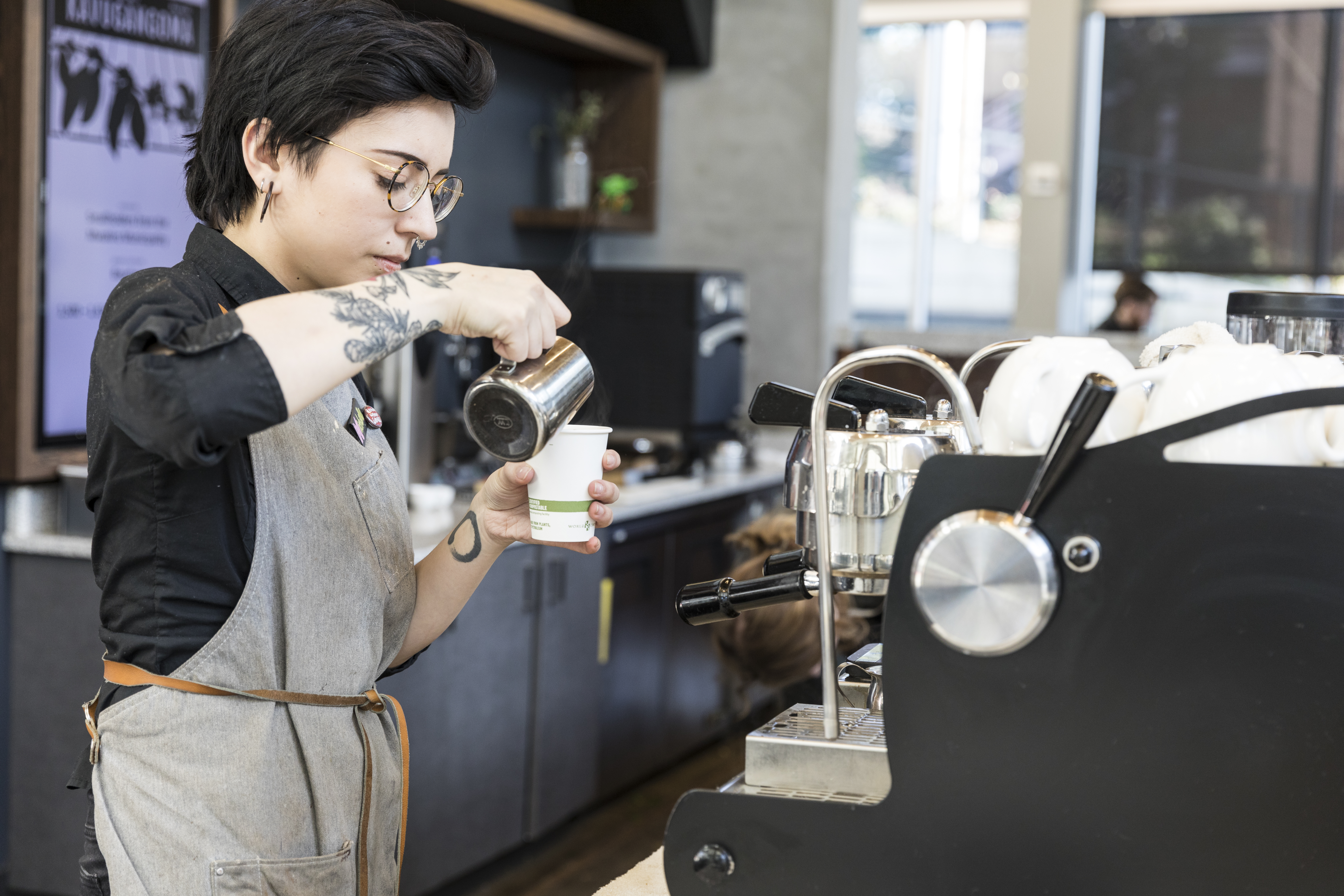 Barista pours coffee into a cup