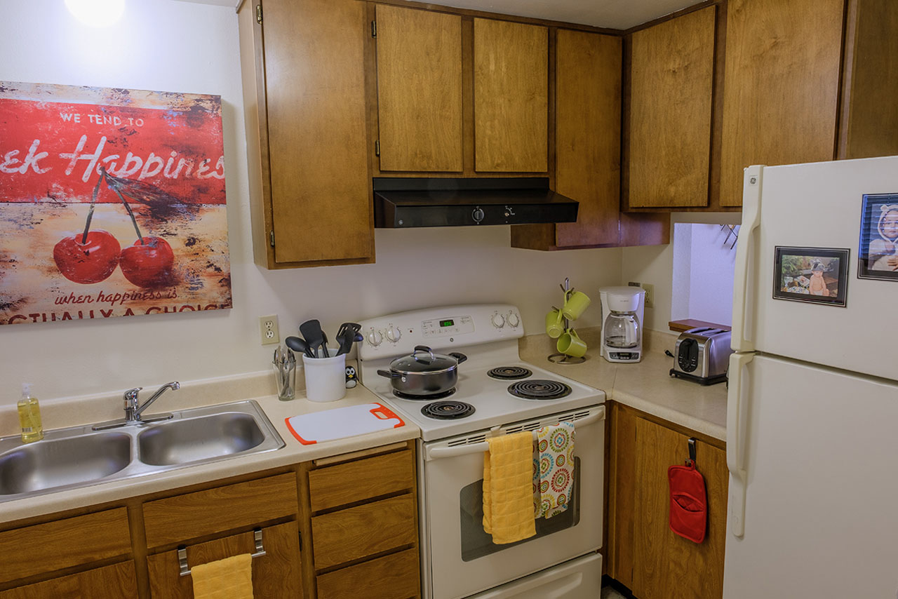 A kitchen in Blakeley Village with wood cabinets and white appliances