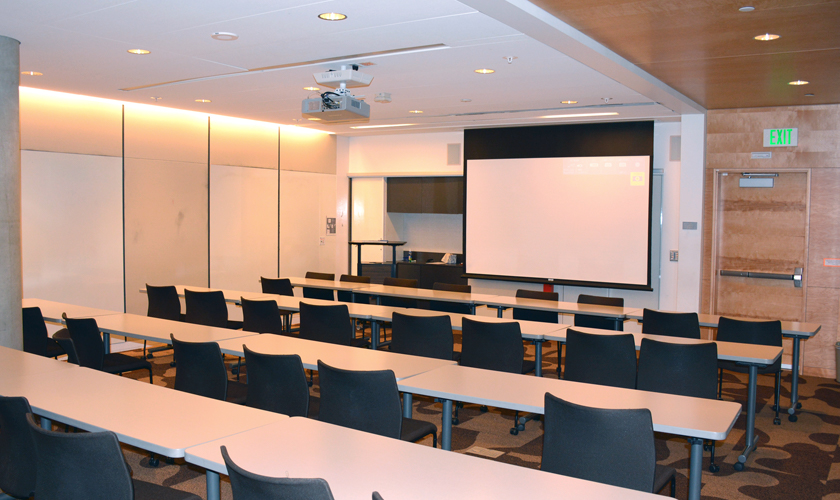 A room with desks, chairs, and projector.