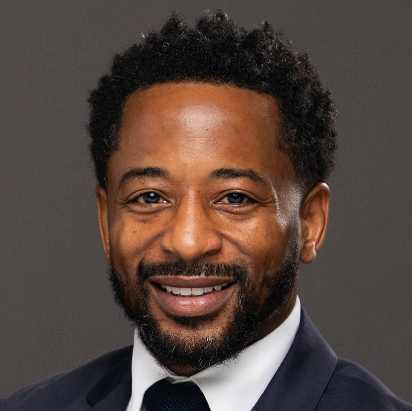 Kyle Boone smiling in front of gray background.