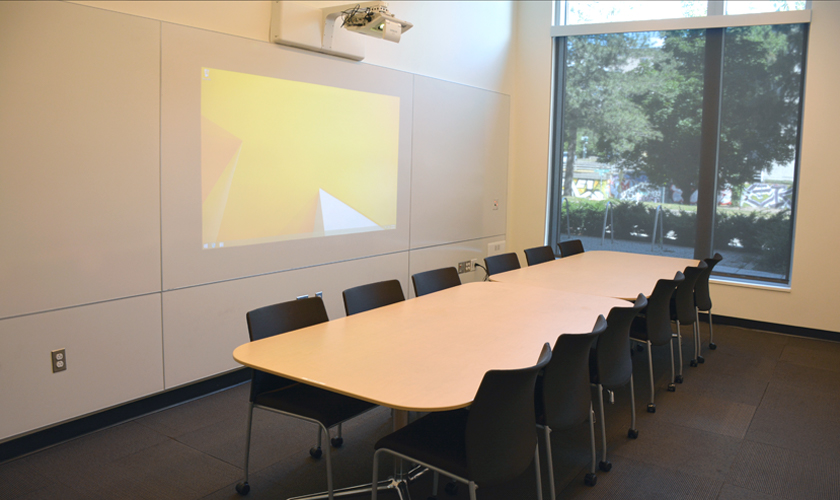 A small room with table, chairs, and projector.