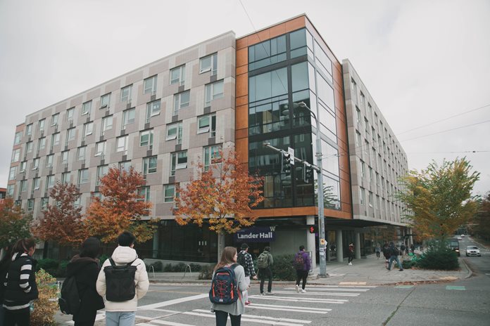 Students walking towards gray and brown building