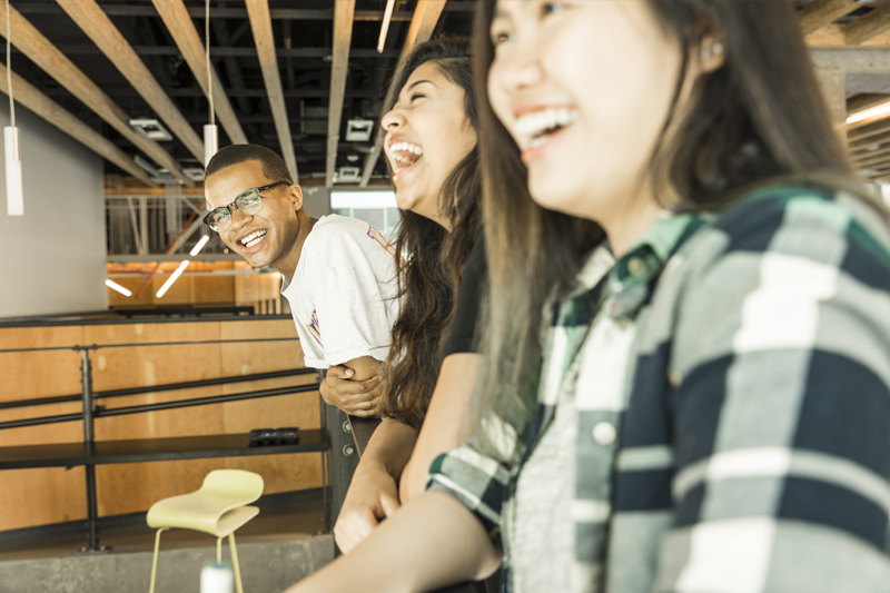 Three students laughing and smiling in Area 01.