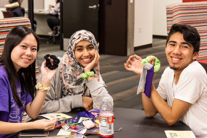 Three students hold up scrunchies.