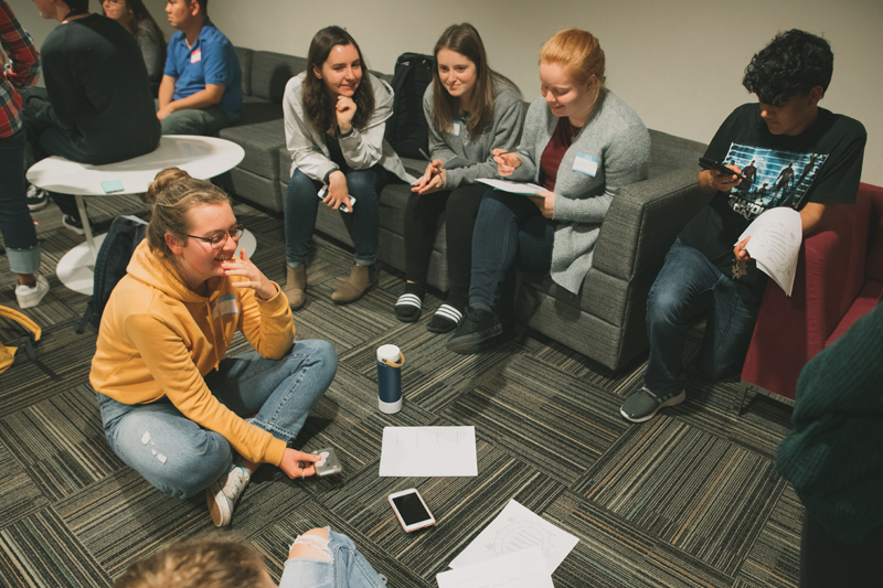 Students talking and smiling on couches at a Hall Council Meeting.