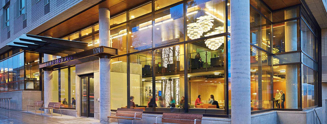 A group of people sitting at chairs inside the windows of a building.