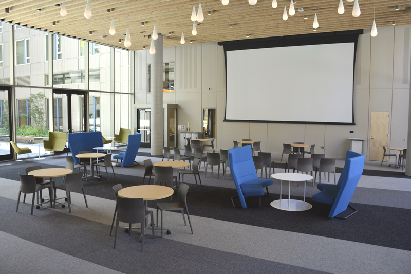 A large room with tables, chairs, and a projector.