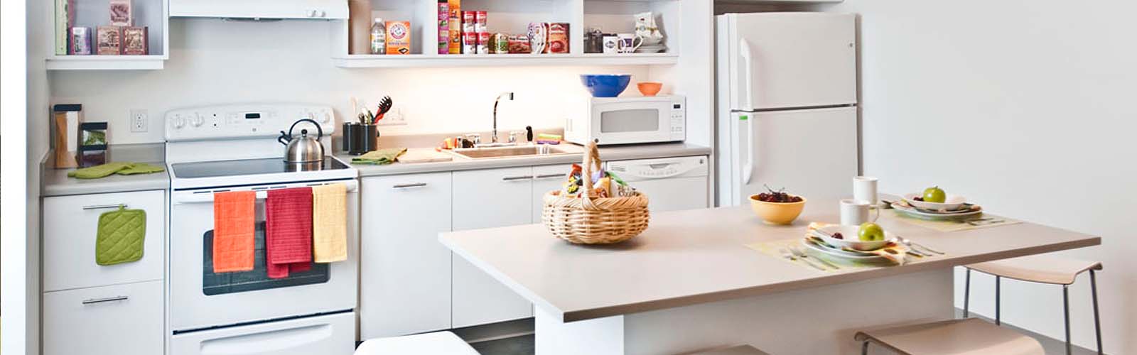 Apartment kitchen with white cabinets and appliances.