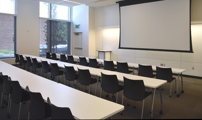 A room with desks, chairs, and projector.