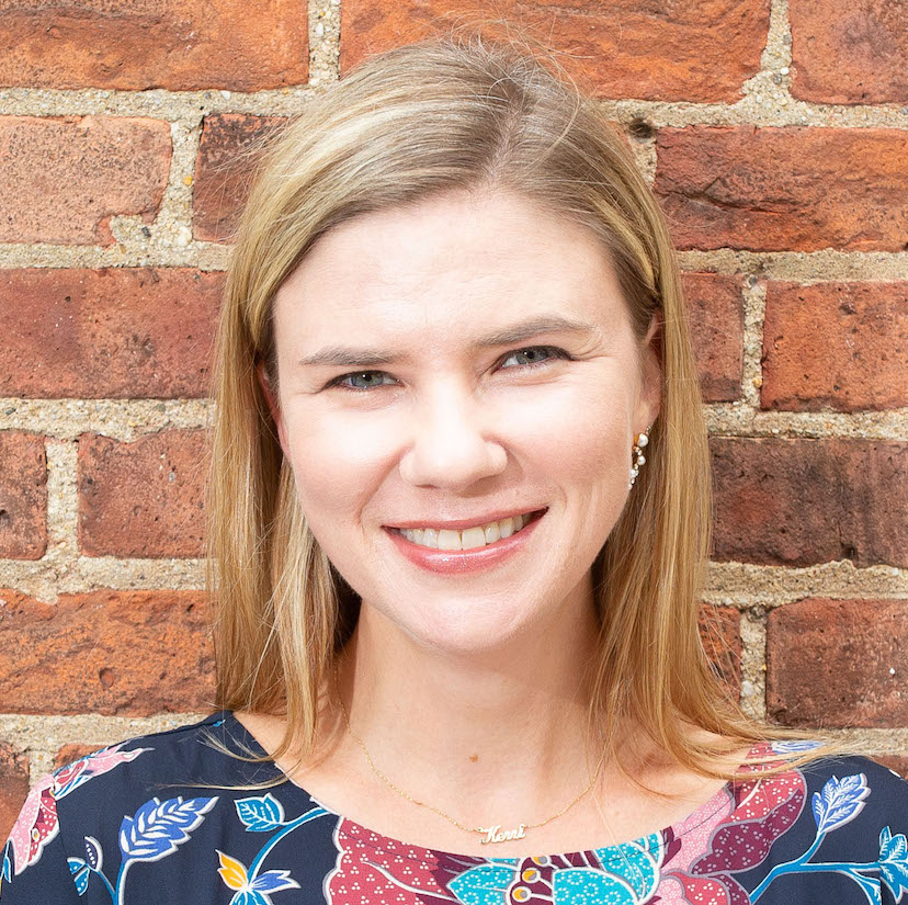 Kerri Smith smiling in front of brick background.