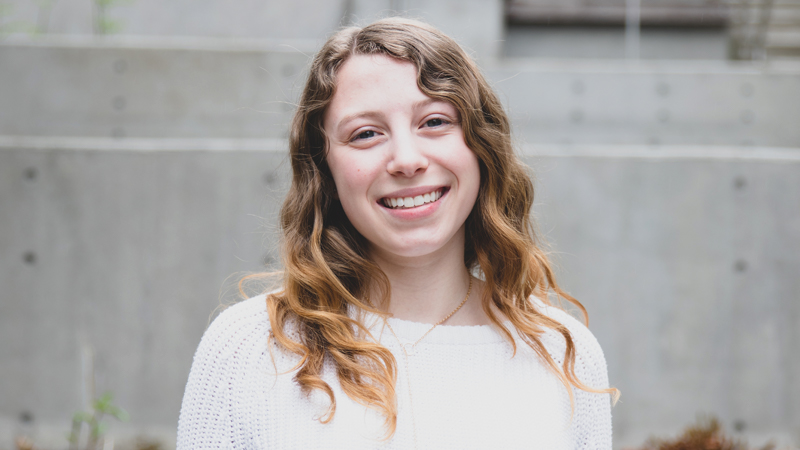 A student wearing a white shirt smiling.