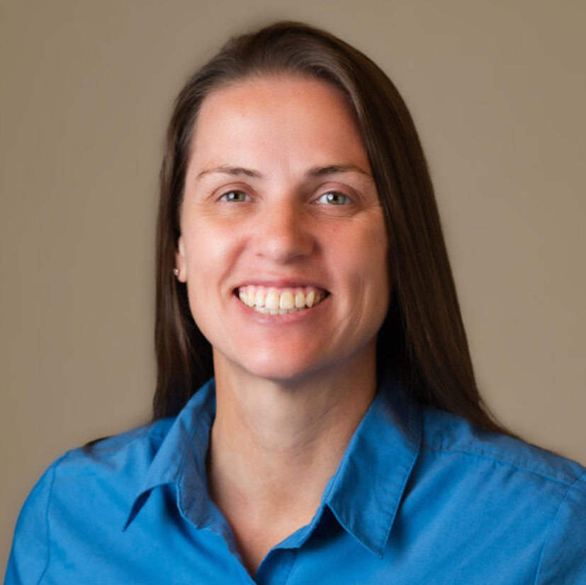 Christine Bender smiling in front of tan background.