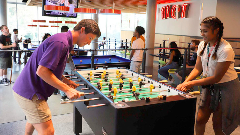 Students playing foosball and pool in the Game Lab