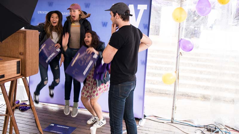 Students jumping in front of a UW banner at Dawg Daze.