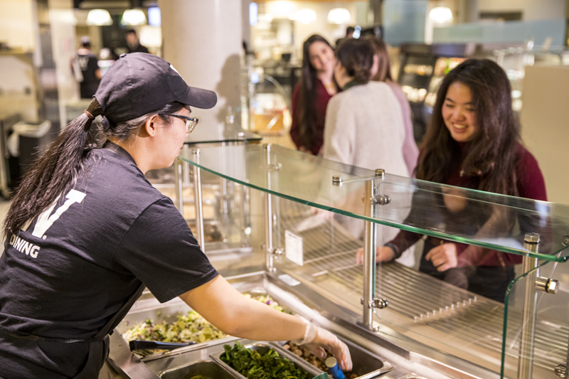 A UW Dining employee serves a customer.