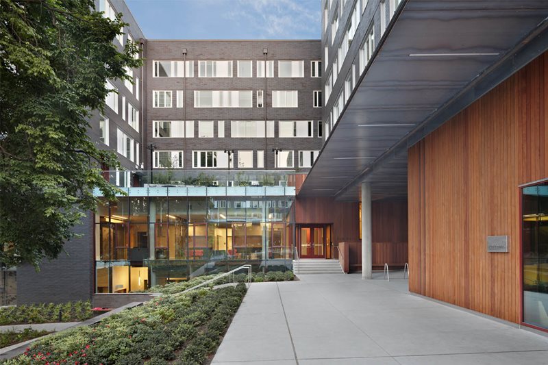 A gray building with a walkway and trees.