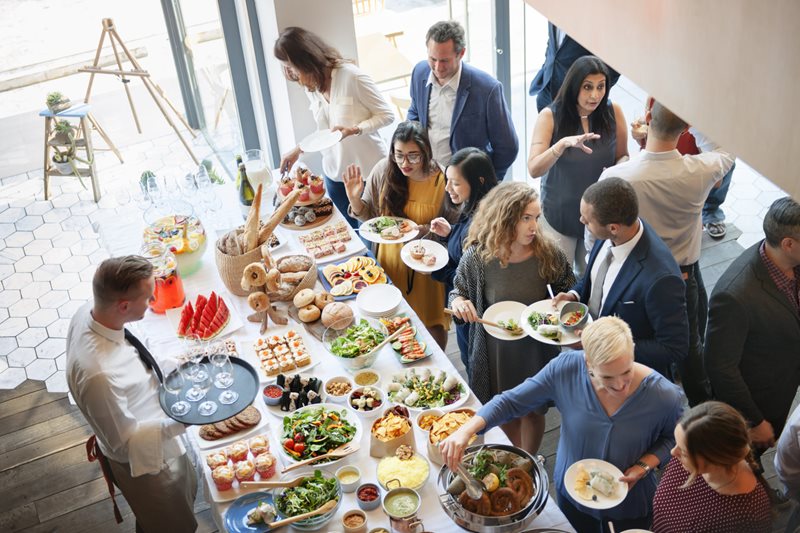 Group of people at a custom department event with food on table.