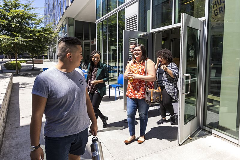 Graduate students coming out of Husky Grind Coffee at Mercer Court