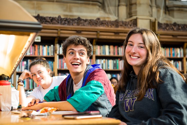 Students smile sitting in Suzzallo Library.