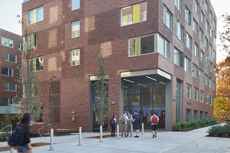 Students standing outside a brown building.