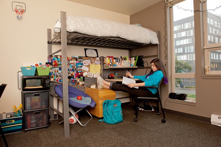 A student studies at her desk in her dorm room.