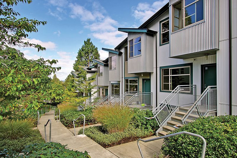 A gray building with stairs and trees.